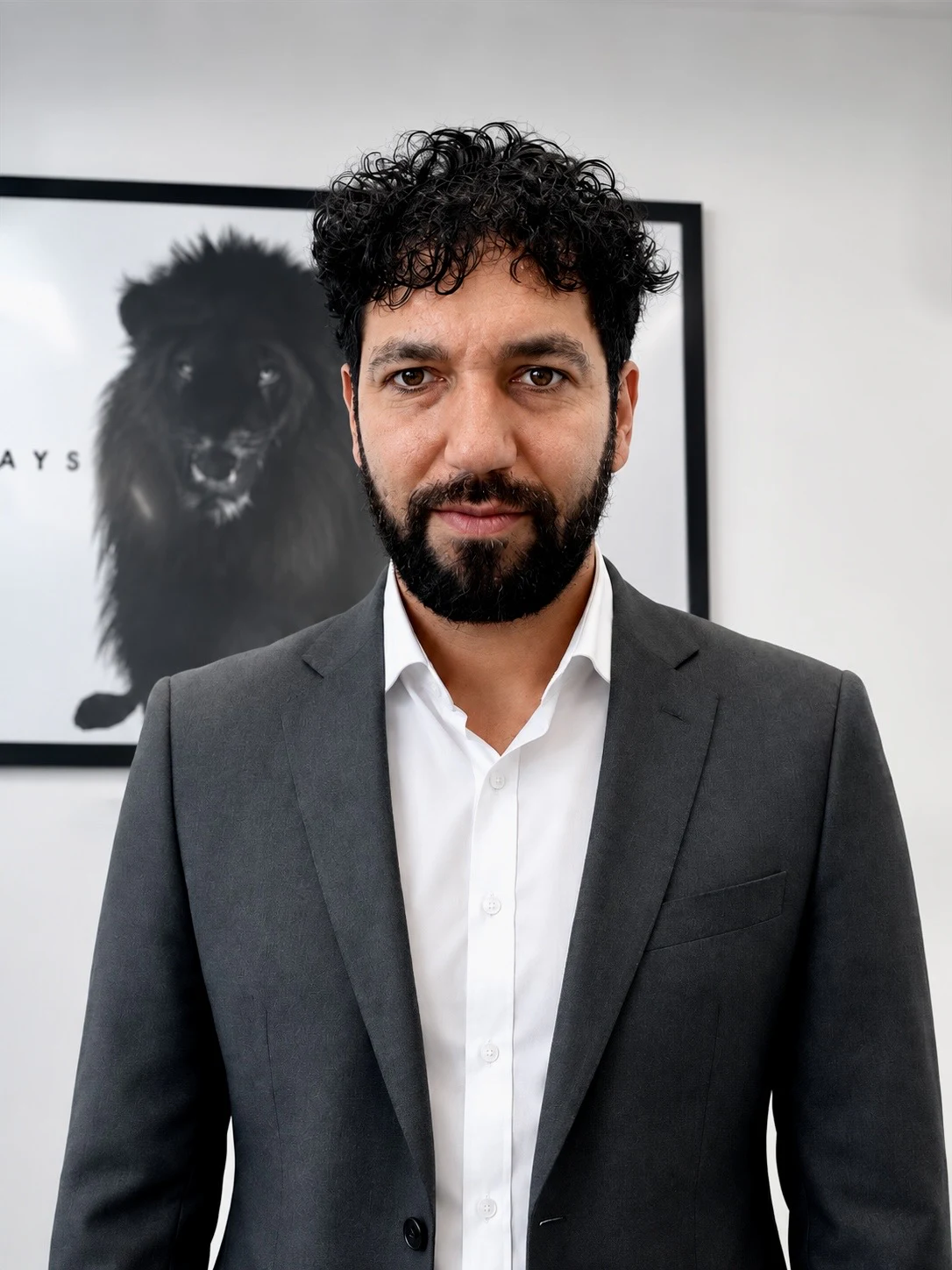 Portrait rapproché de Mehdi B. en costume devant une photographie de lion